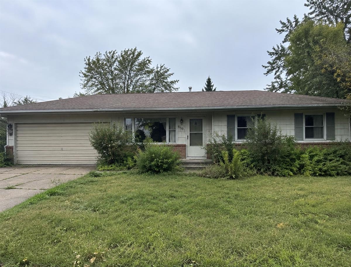 Dated ranch-style home with overgrown shrubs that could use cosmetic updates